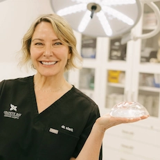 Dr. Clark holding breast implants