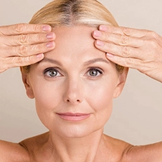 mature woman with minimal wrinkles touching forehead