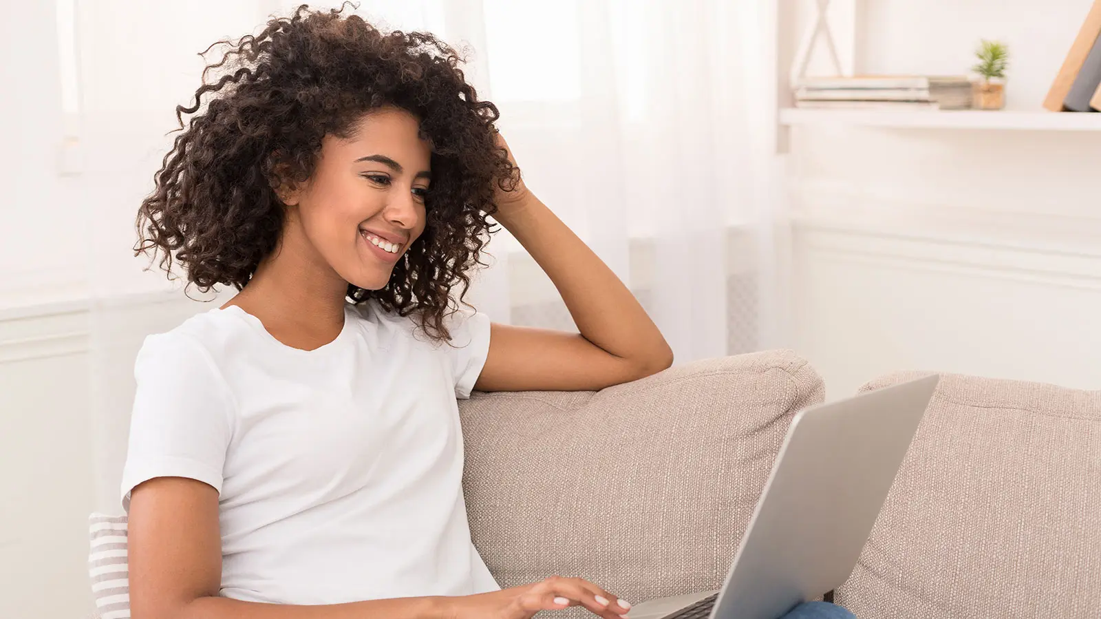 Pretty african-american woman using laptop while relaxing on sofa