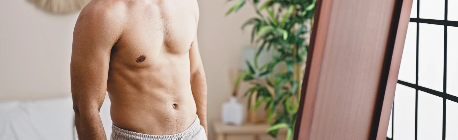 man with toned midsection looking in mirror