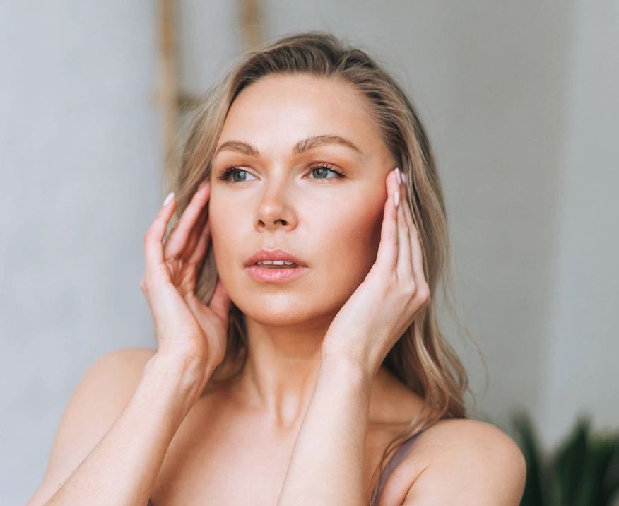 35 year-old woman touching face and looking at botox results in mirror