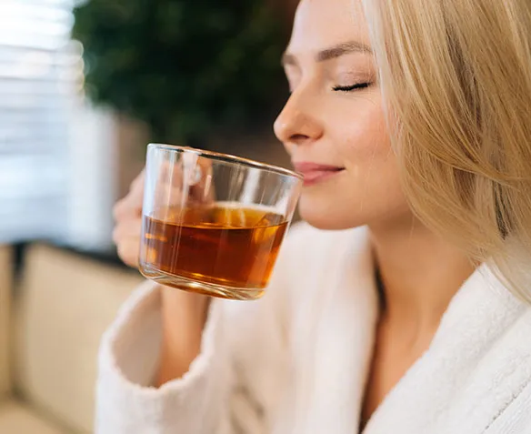 blonde woman with eyes closes drinking tea
