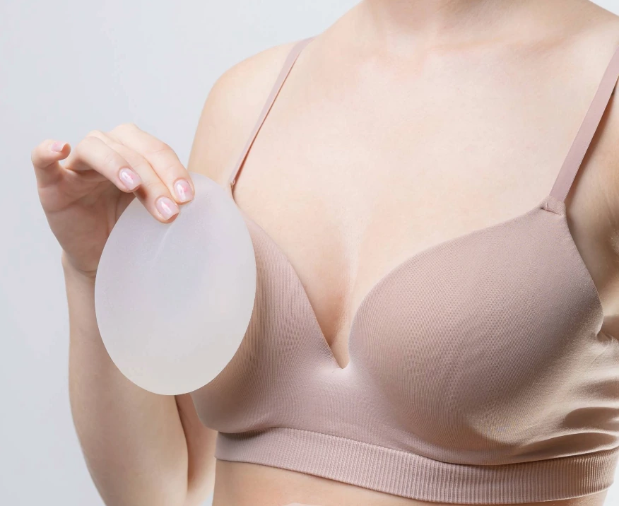 closeup of woman in bra holding breast implant