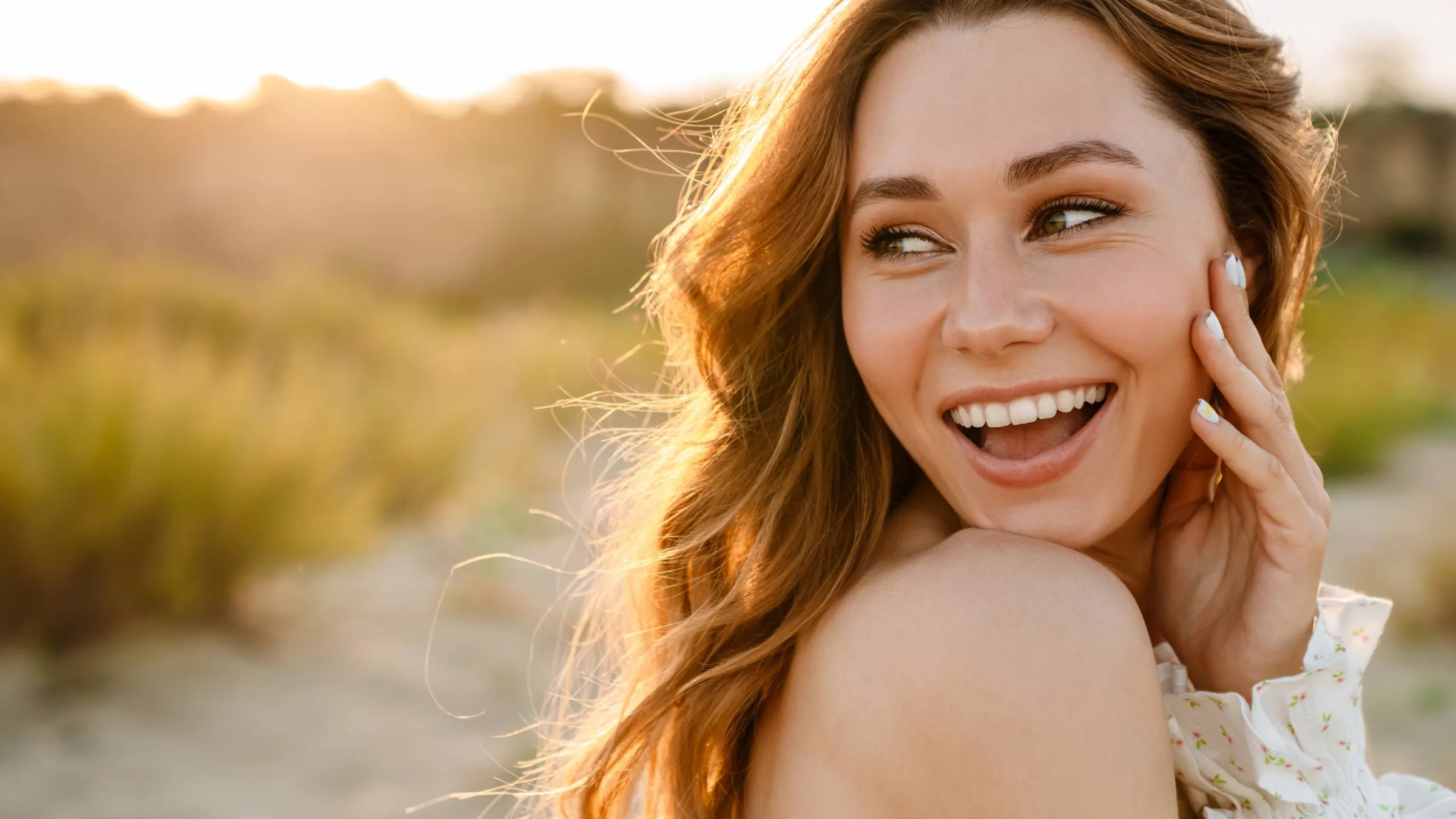 joyful woman during sunset with flawless skin touching face