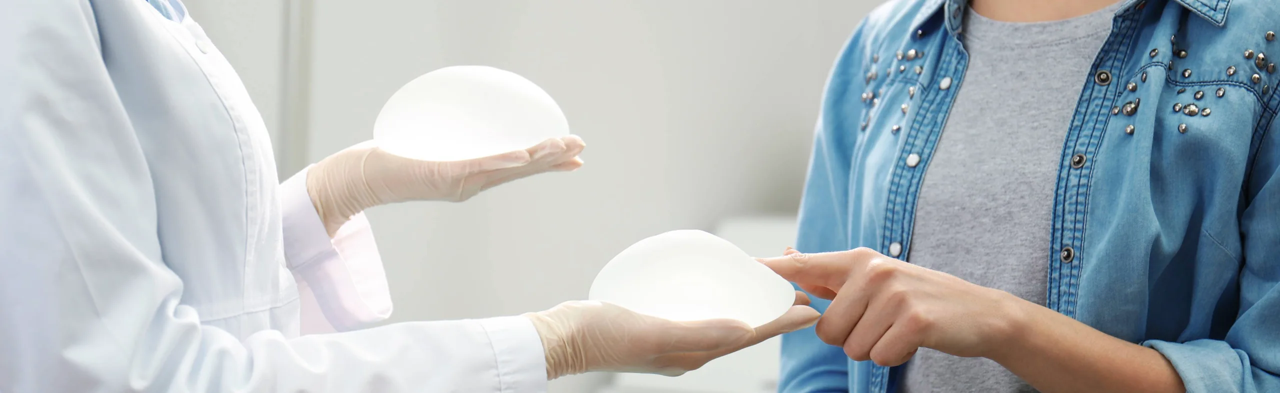 plastic surgeon showing woman different breast implant selections