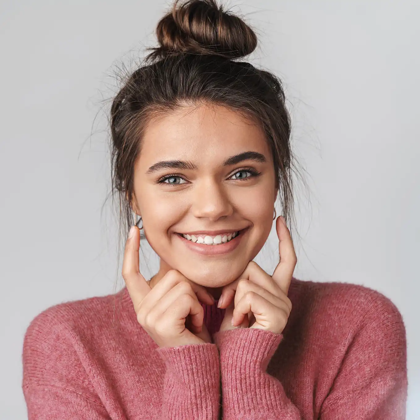 happy teen girl wearing hair in a bun and touching ears